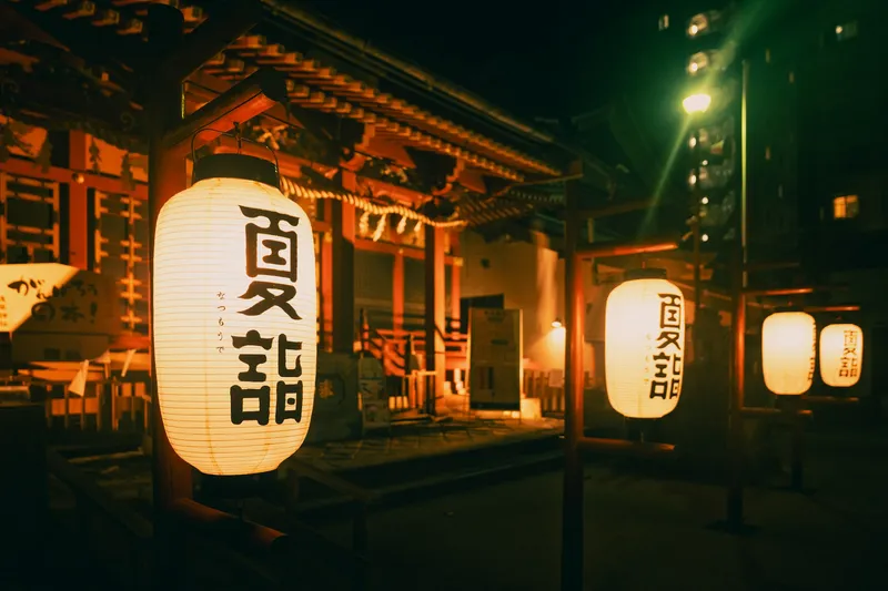 Lanterns illuminate a shrine building at night in Asakusa, Tokyo