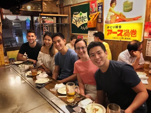 Travelers seated at a counter enjoying food and drinks at a traditional izakaya in Japan