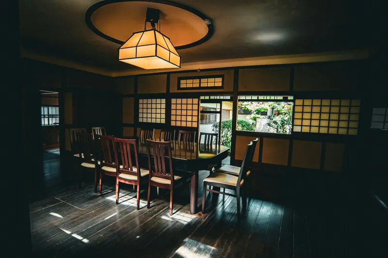A long dining table set beneath a warm lantern light in a traditional Japanese room, Nara